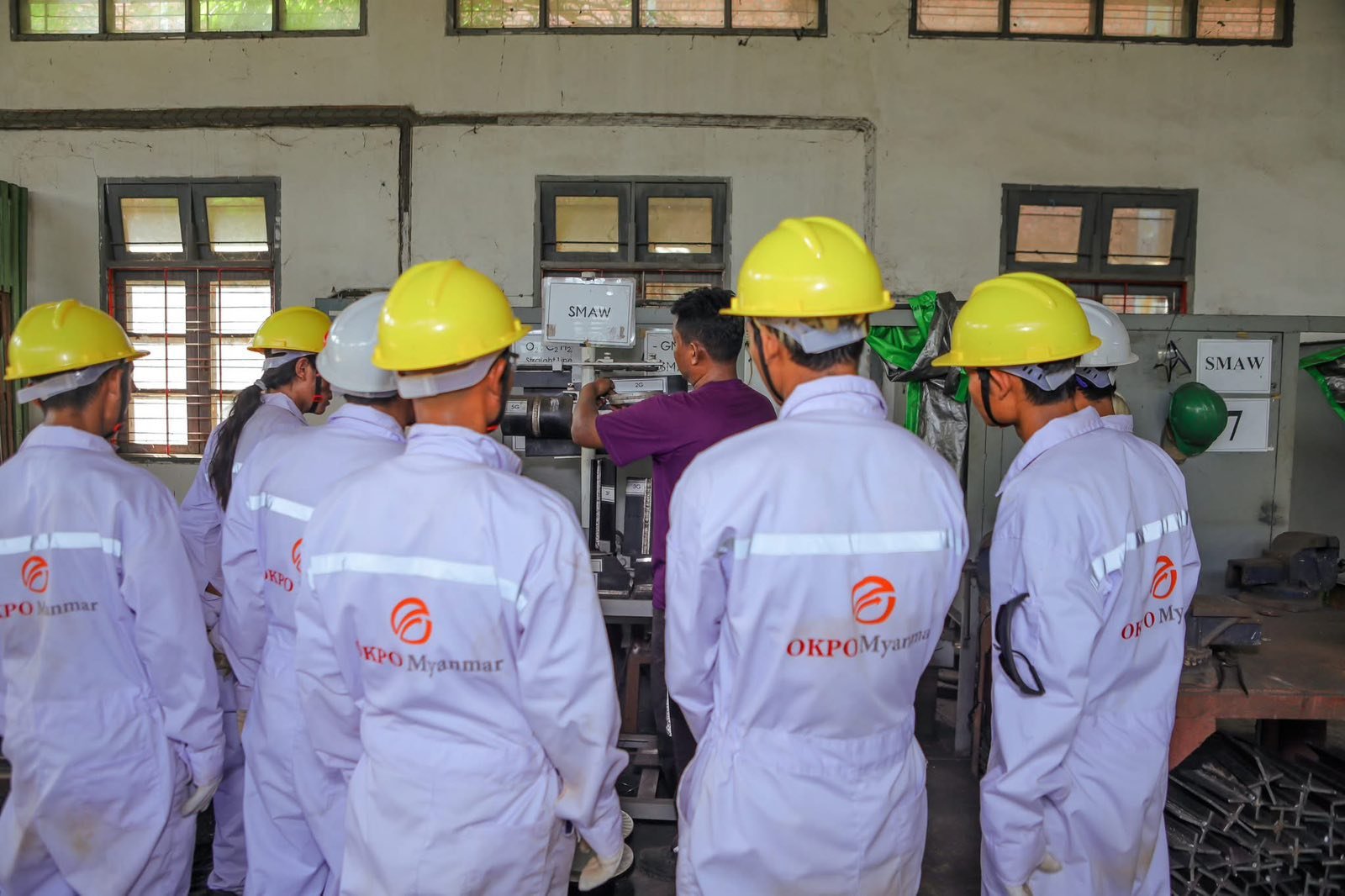 People in safety clothing observing an industrial workshop demonstration