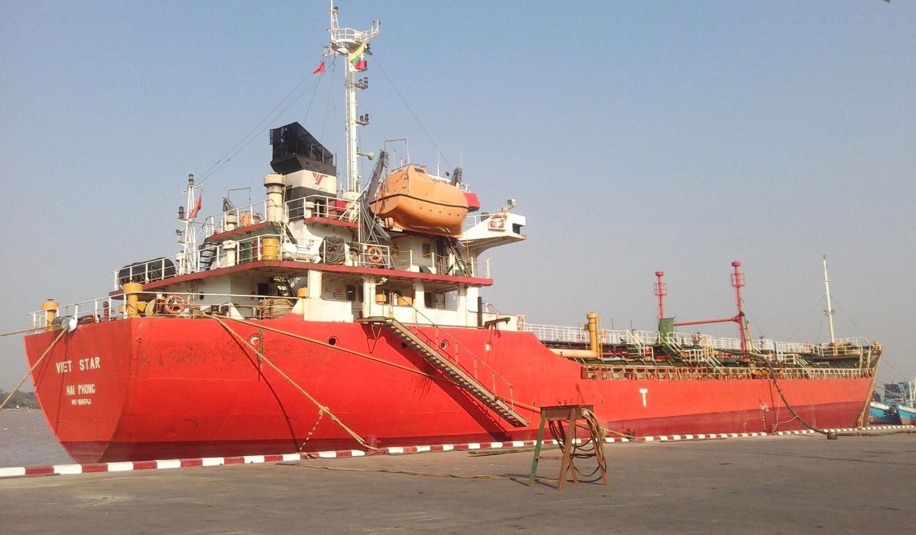 Red transport vessel moored at a riverside quay
