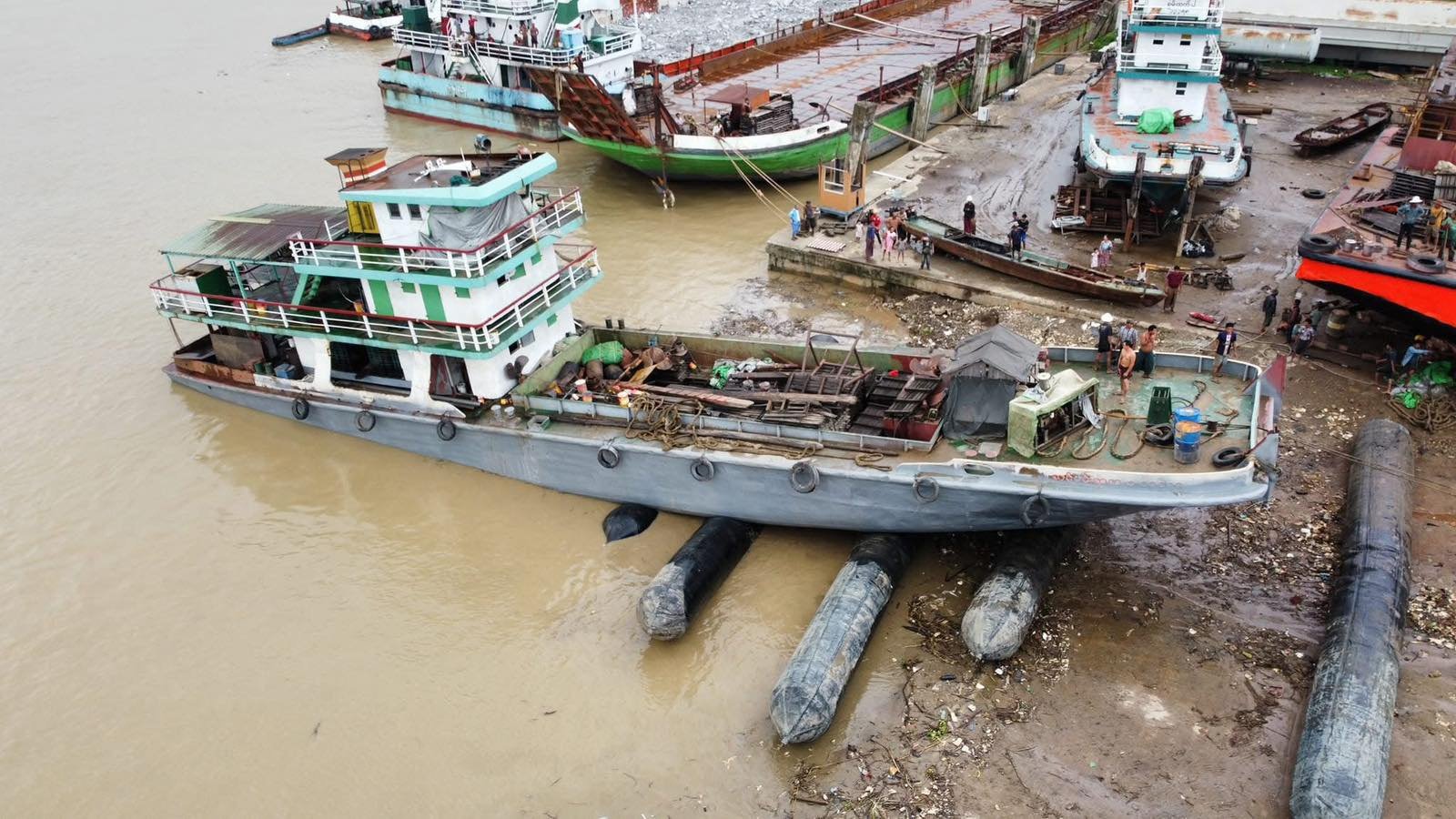 Large vessel supported on inflatable rollers at a waterside work area