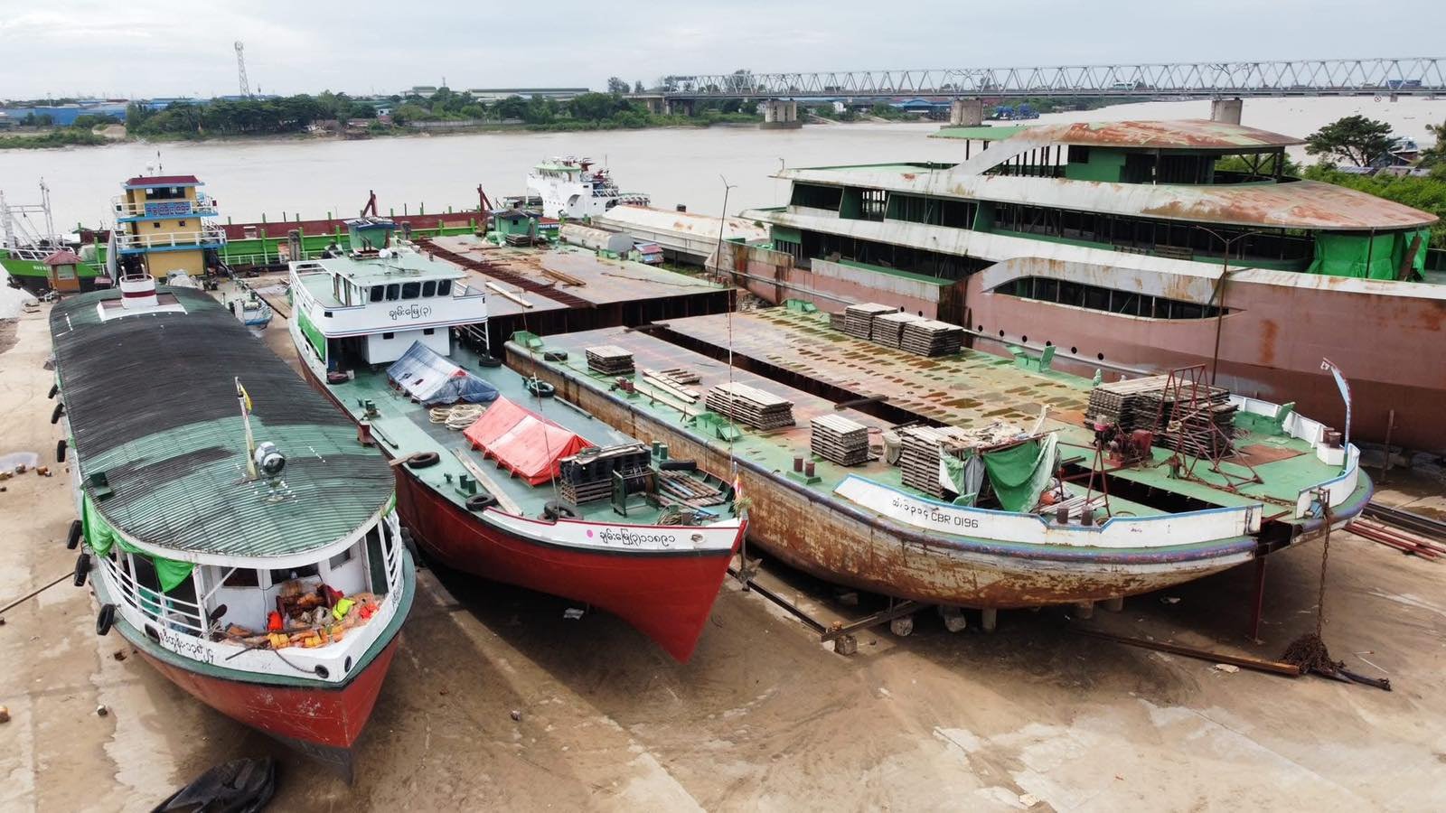 Large vessels resting in a shipyard beside a river