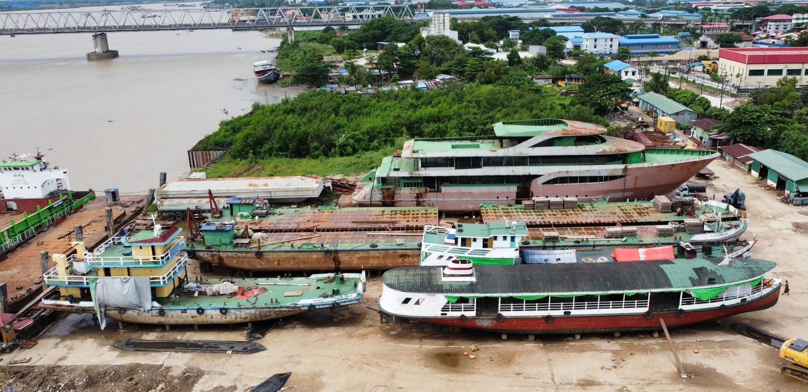 Aerial view of multiple vessels in a riverside shipyard